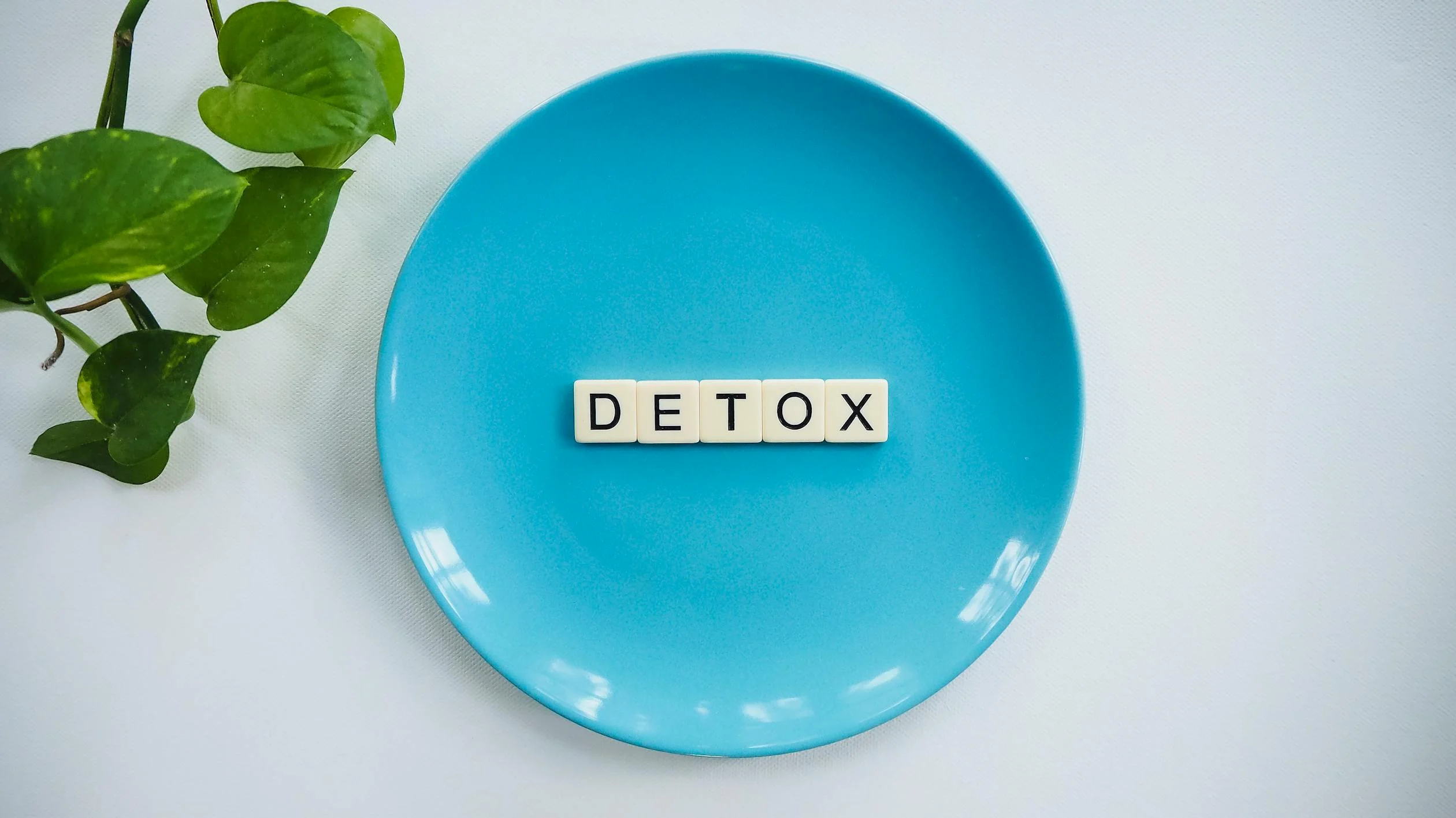 Scrabble pieces on a blue bowl spelling out 'DETOX'